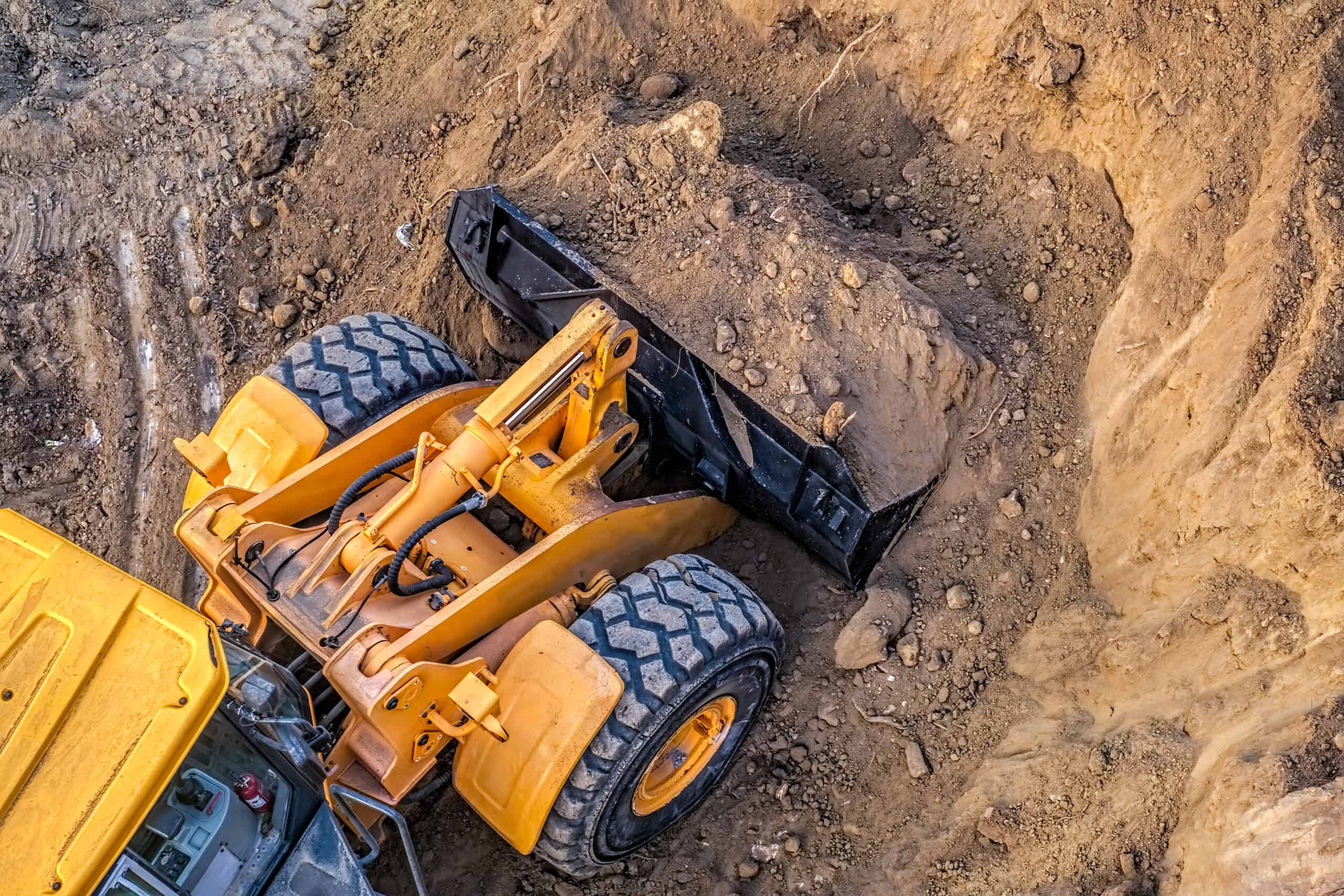 Bagger schaufelt Erde in einem Erdloch auf einer Baustelle.