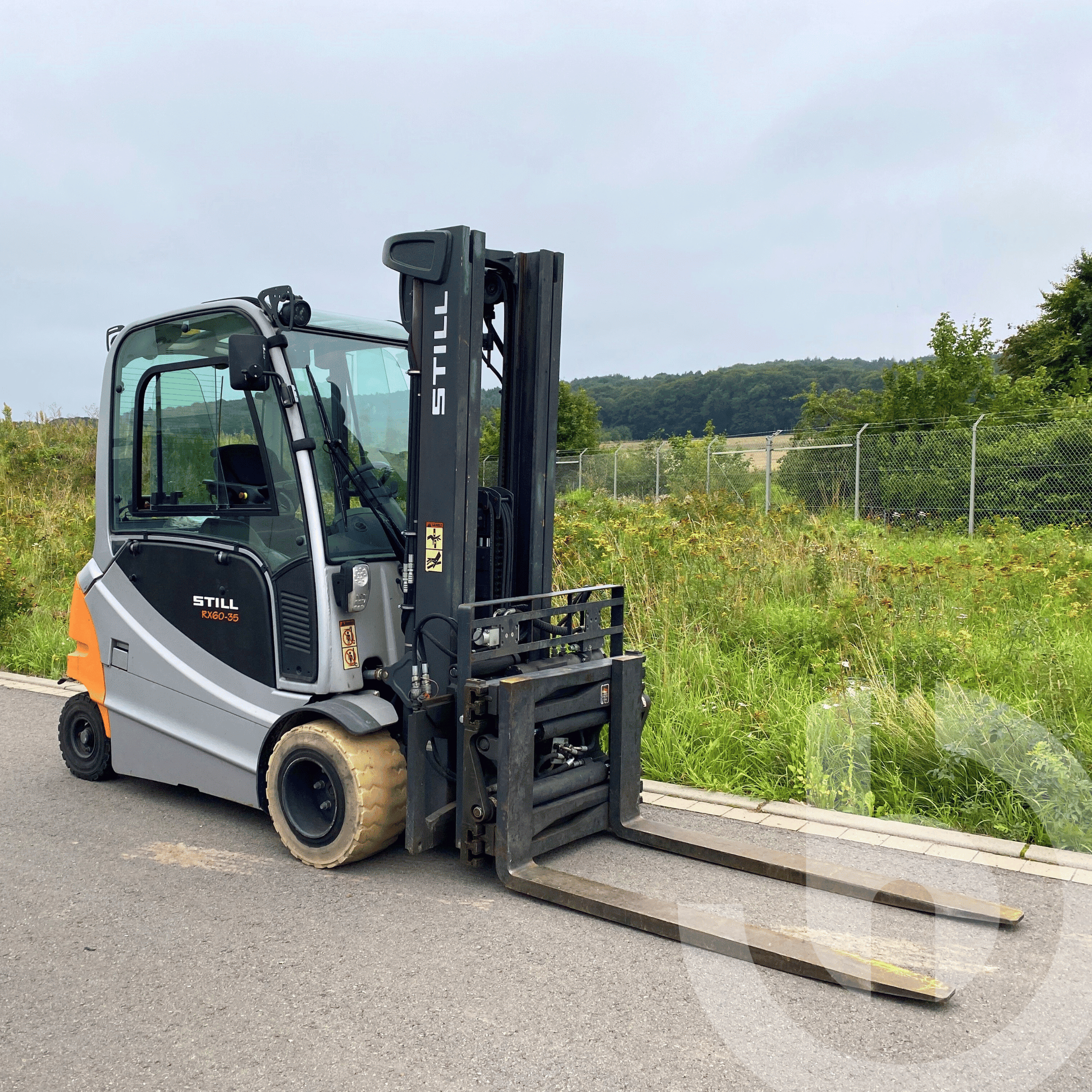 Auf dem Bild ist der STILL RX 60-35 Gabelstapler von vorne auf einem offenen Gelände bei Tageslicht zu sehen. Der Elektrostapler eignet sich dank seiner starken Motorleistung und wendigen Bauweise ideal für den Einsatz im Freien sowie in anspruchsvollen Logistik- und Produktionsumgebungen. Mit einer Tragkraft von bis zu 3,5 Tonnen verbindet der RX 60-35 Leistung und Komfort für effiziente Arbeitsprozesse. STILL RX 60-35 Elektrogabelstapler in Frontansicht auf offenem Gelände bei Tageslicht.